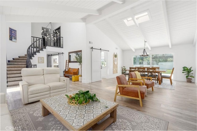 living room featuring a barn door, a chandelier, high vaulted ceiling, and light wood-type flooring