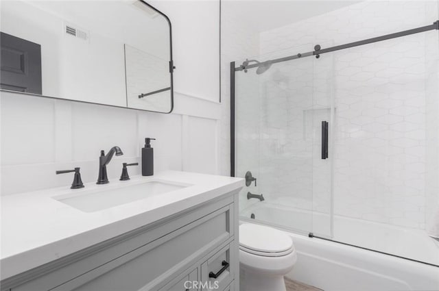 full bathroom featuring vanity, bath / shower combo with glass door, and toilet