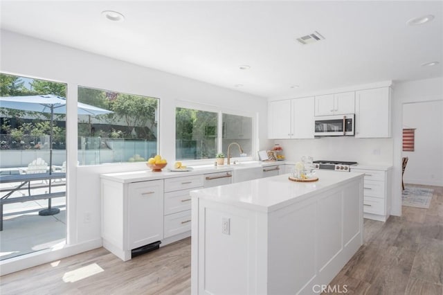 kitchen featuring white cabinetry, a wealth of natural light, a kitchen island, and light hardwood / wood-style flooring