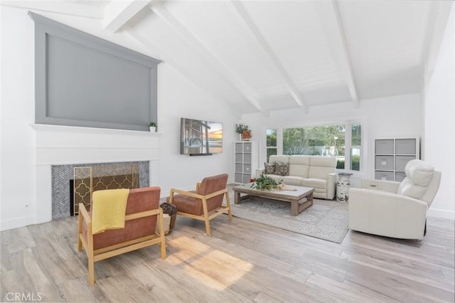 living room featuring high vaulted ceiling, light hardwood / wood-style flooring, a tile fireplace, and beamed ceiling