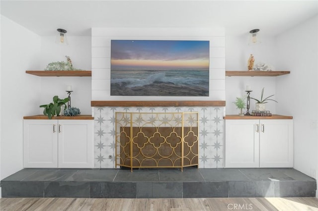 unfurnished living room with a tiled fireplace and dark hardwood / wood-style flooring