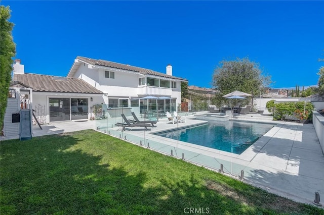 rear view of house featuring a patio area, a balcony, and a lawn