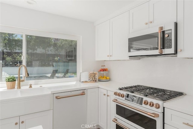 kitchen with white cabinetry, white appliances, a healthy amount of sunlight, and sink