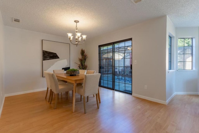 dining room featuring a chandelier, light hardwood / wood-style flooring, and a textured ceiling