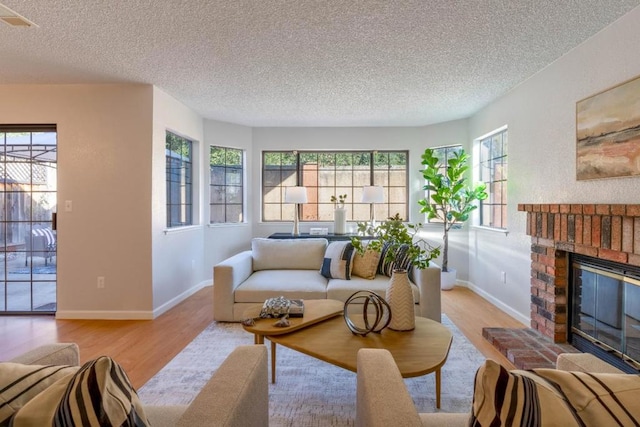 living room with a fireplace, light hardwood / wood-style floors, and a textured ceiling