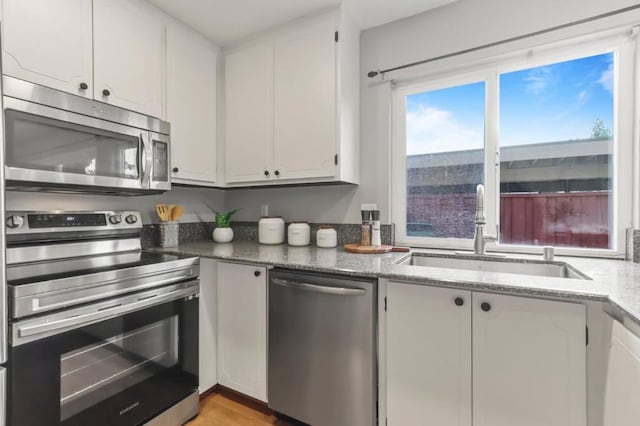 kitchen featuring appliances with stainless steel finishes, sink, dark stone counters, and white cabinets