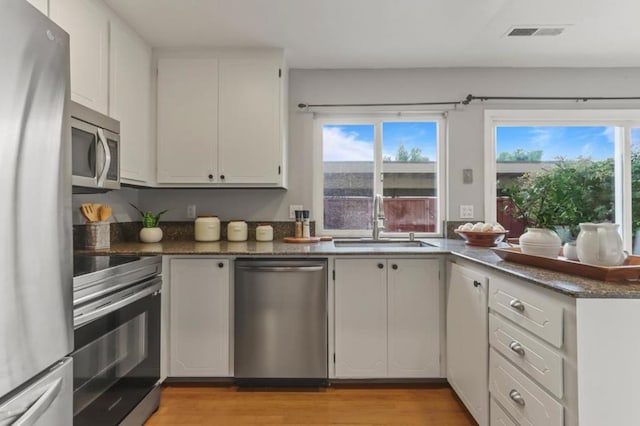 kitchen featuring sink, stainless steel appliances, light hardwood / wood-style floors, and white cabinets