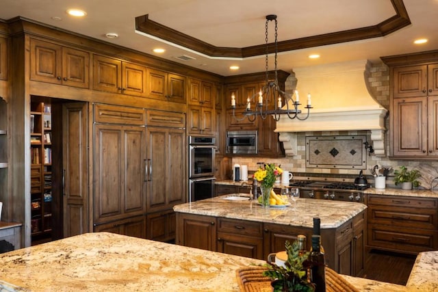 kitchen featuring hanging light fixtures, a tray ceiling, ornamental molding, and a kitchen island