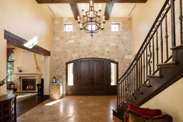 entrance foyer featuring a notable chandelier, beam ceiling, and a towering ceiling