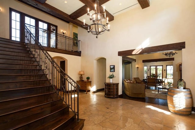 interior space with beam ceiling, coffered ceiling, a high ceiling, and a chandelier