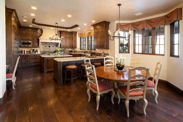 dining area with dark hardwood / wood-style floors, a notable chandelier, and a tray ceiling