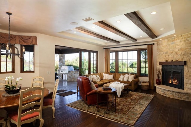 living room featuring dark hardwood / wood-style flooring, a chandelier, and a stone fireplace