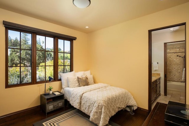 bedroom with ensuite bath and wood-type flooring