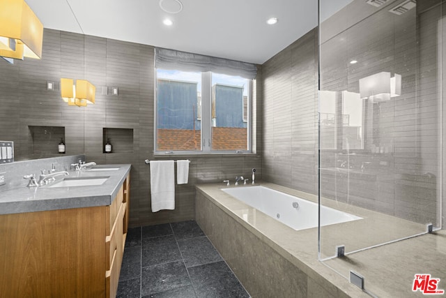 bathroom with vanity, tile walls, tile patterned floors, and tiled bath