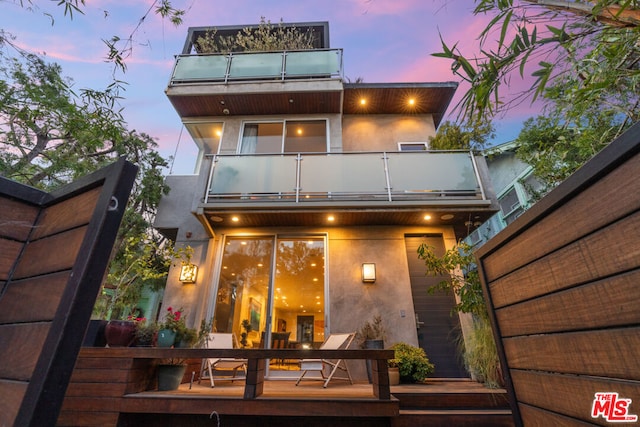 back house at dusk featuring a balcony