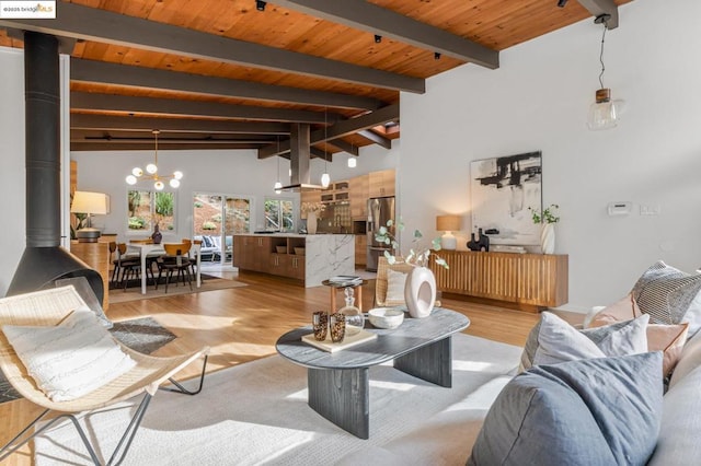 living room with a wood stove, an inviting chandelier, wooden ceiling, beamed ceiling, and light wood-type flooring