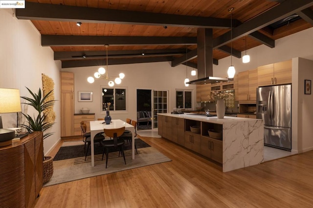 kitchen featuring beamed ceiling, stainless steel fridge, hanging light fixtures, a center island with sink, and wooden ceiling