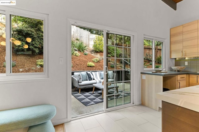 doorway with vaulted ceiling and light tile patterned floors