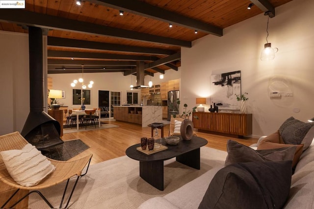 living room with wood ceiling, lofted ceiling with beams, light hardwood / wood-style floors, and a wood stove