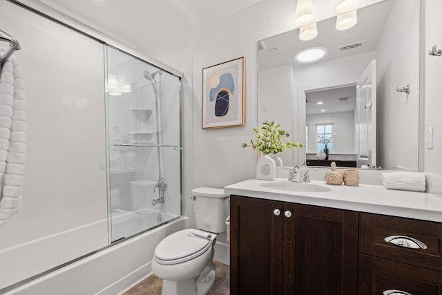 full bathroom featuring vanity, combined bath / shower with glass door, and toilet