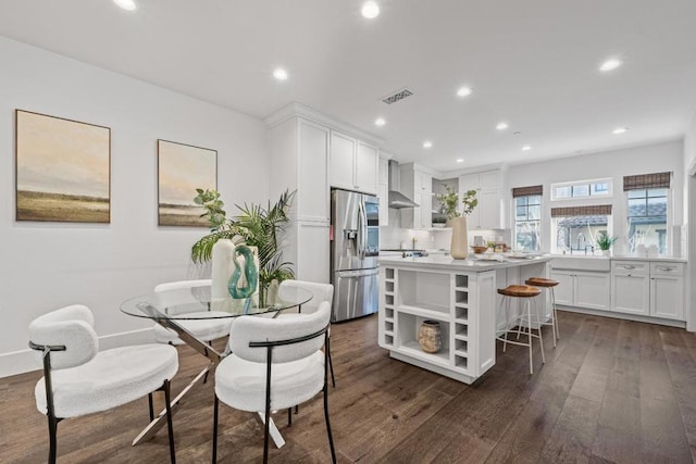 kitchen with a breakfast bar area, a center island, stainless steel fridge with ice dispenser, dark hardwood / wood-style floors, and white cabinets