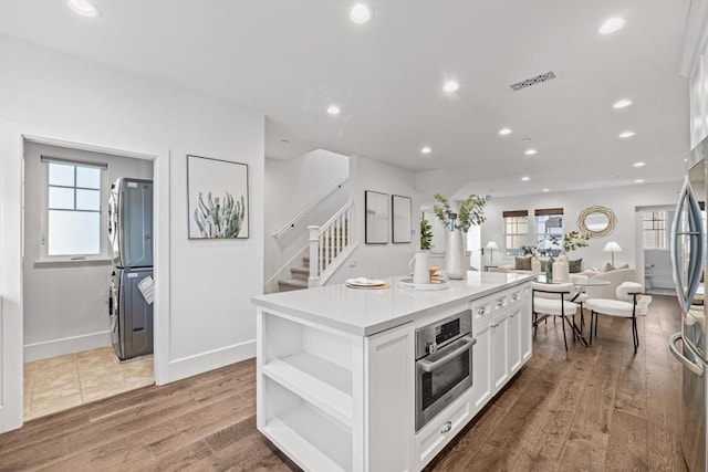 kitchen with stainless steel appliances, wood-type flooring, a center island, and white cabinets