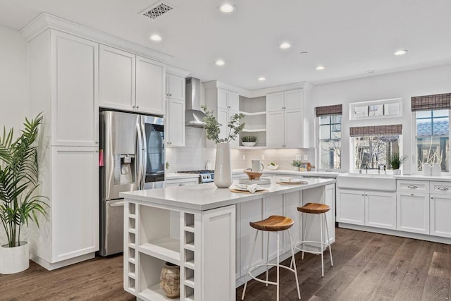 kitchen with white cabinetry, wall chimney range hood, stainless steel fridge, and sink