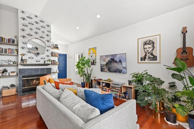 living room featuring dark wood-type flooring, lofted ceiling, and a tiled fireplace