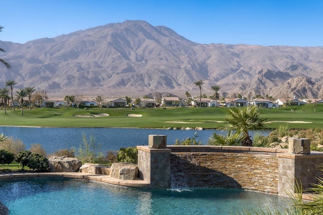 view of swimming pool featuring a yard, a water and mountain view, and pool water feature