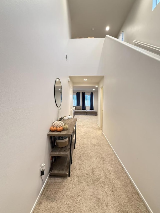 corridor featuring light carpet and a high ceiling