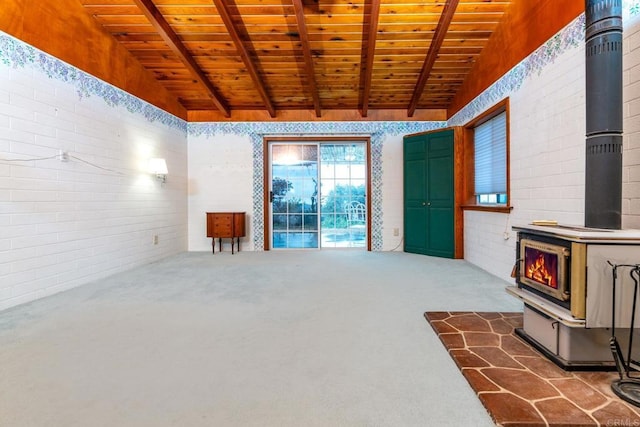 unfurnished living room with dark colored carpet, wood ceiling, lofted ceiling with beams, a wood stove, and brick wall