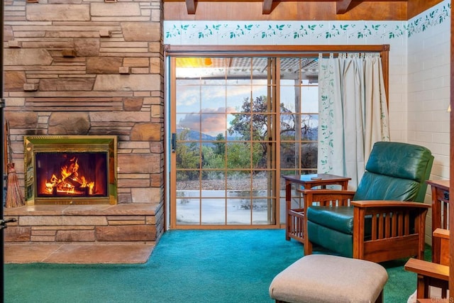 sitting room featuring a stone fireplace and carpet floors