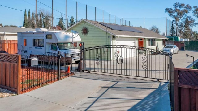 view of gate featuring a garage and solar panels