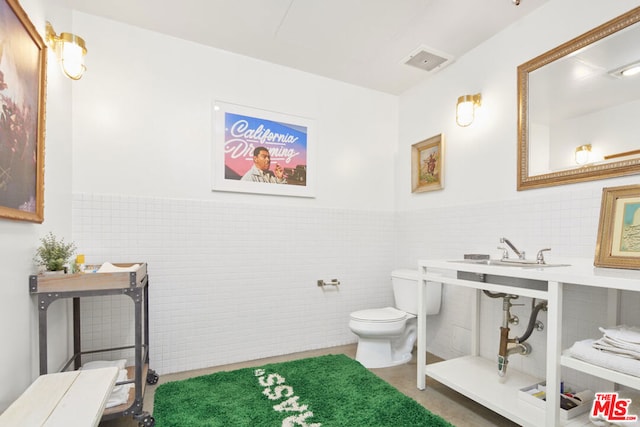 bathroom featuring sink, tile walls, and toilet