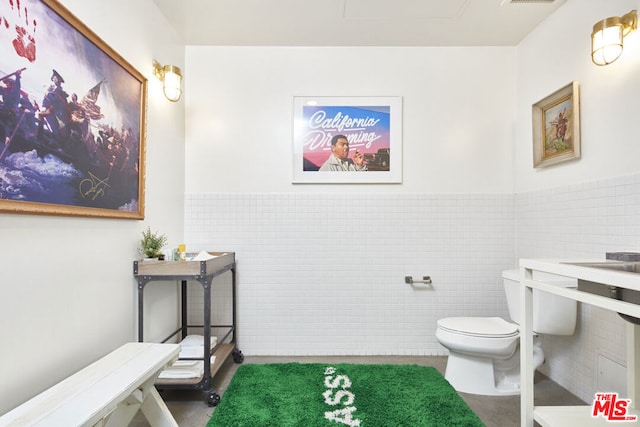 bathroom featuring tile walls and toilet