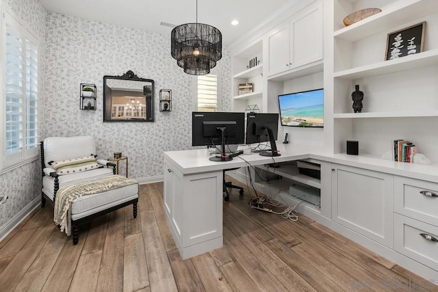 office space featuring light wood-type flooring and built in shelves