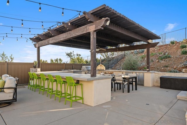 view of patio with a pergola, an outdoor bar, and exterior kitchen