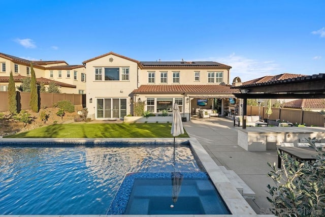 back of house with a fenced in pool, a lawn, a patio, a water view, and solar panels