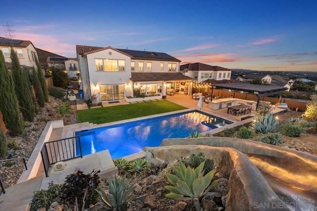 pool at dusk with a yard, a patio, and an in ground hot tub