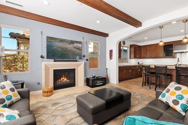 living room featuring a high end fireplace, sink, and beam ceiling