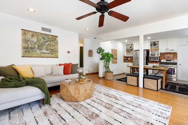 living room with light hardwood / wood-style flooring and ceiling fan