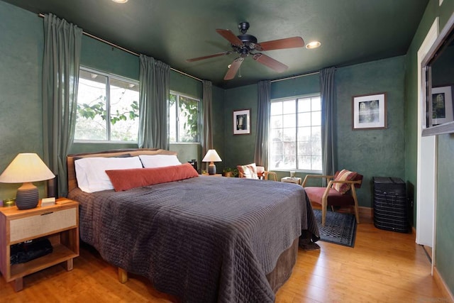 bedroom featuring multiple windows, light hardwood / wood-style flooring, and ceiling fan