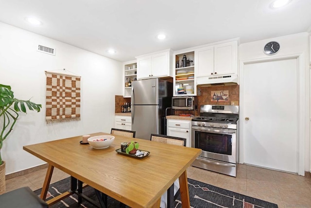 kitchen featuring stainless steel appliances, white cabinetry, tile patterned flooring, and backsplash