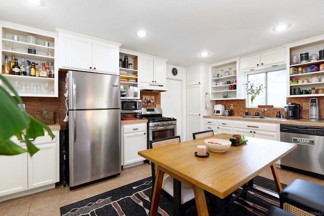 kitchen with light tile patterned flooring, stainless steel appliances, sink, and white cabinets