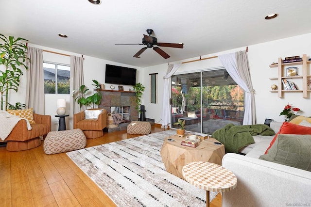 living room with hardwood / wood-style floors, a tile fireplace, and ceiling fan