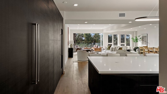 kitchen with dark brown cabinetry, light hardwood / wood-style flooring, and paneled built in fridge