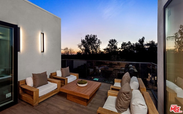 patio terrace at dusk featuring outdoor lounge area and a balcony