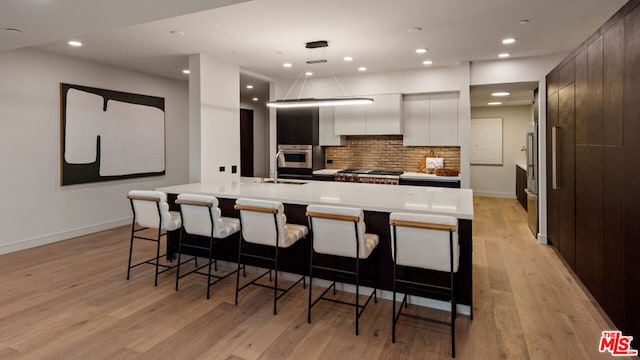 kitchen featuring a kitchen breakfast bar, decorative backsplash, and a large island with sink