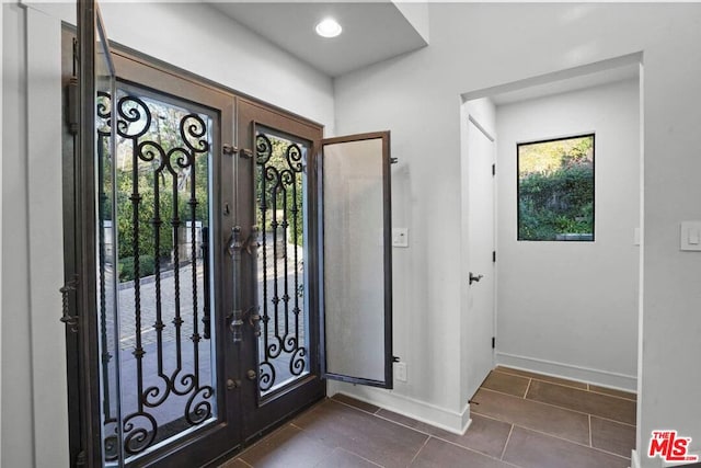 entryway with dark tile patterned flooring and french doors