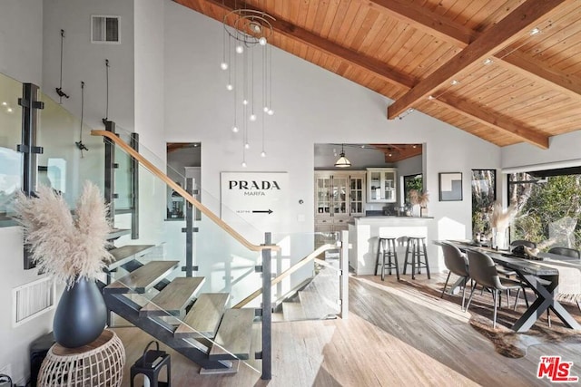 stairway featuring beam ceiling, high vaulted ceiling, hardwood / wood-style flooring, and wooden ceiling